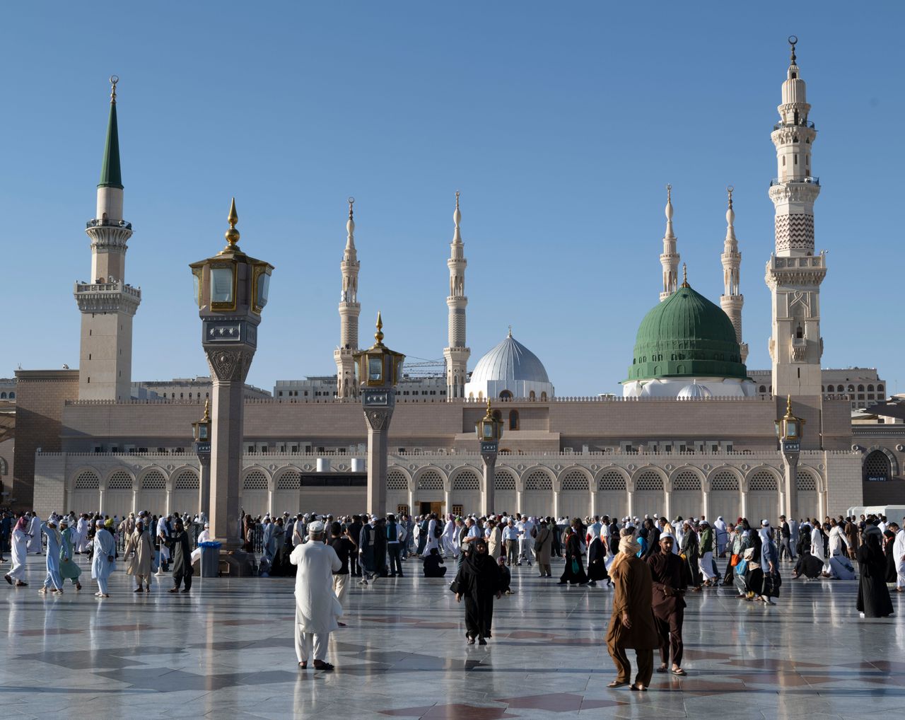 Services Pilgrims gather at the courtyard of Al-Masjid an-Nabawi, showcasing Islamic architecture in Medina, Saudi Arabia.
