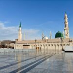 Beautiful view of the Masjid an-Nabawi in Medina with clear blue skies, capturing its iconic domes and minarets.
